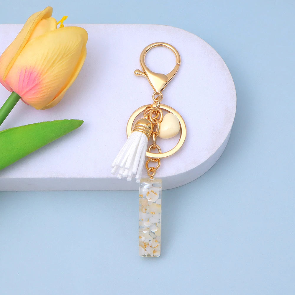 ميدالية مفاتيح بالحروف الـ 26 من الراتنج، دلاية عصرية بلون كريمي بقلب وشرابة، حلقة مفاتيح بحروف من A إلى Z للنساء، زينة للحقيبة وهدية حفلات